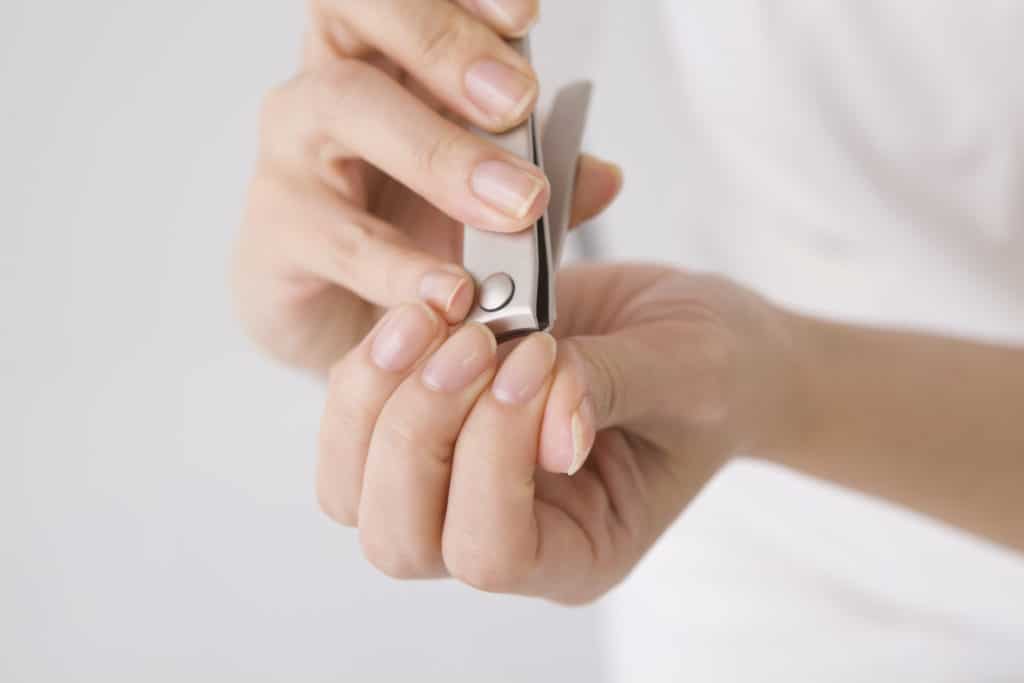 Person schneidet sich die Fingernägel. Bei der Nagelpflege ist Vorsicht geboten.