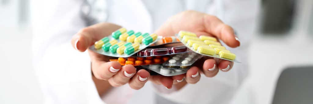 Apothekerin zeigt Tabletten gegen Nagelpilz