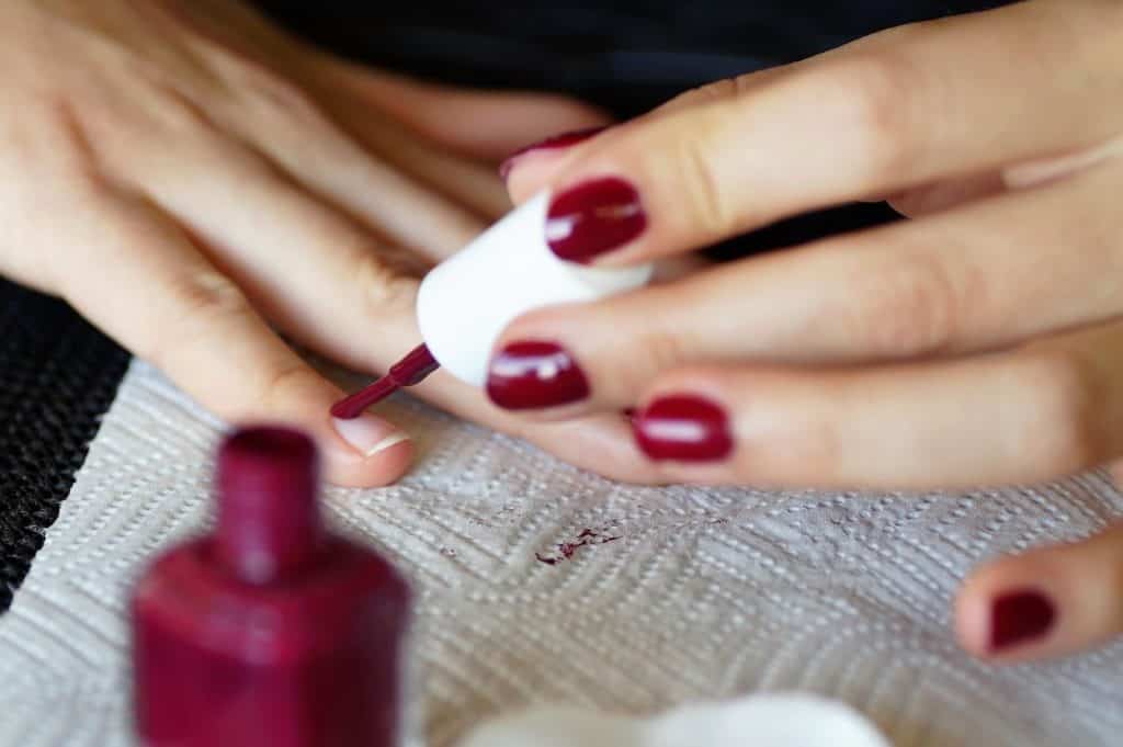 Maniküre, eine Frau lackiert sich die Nägel rot